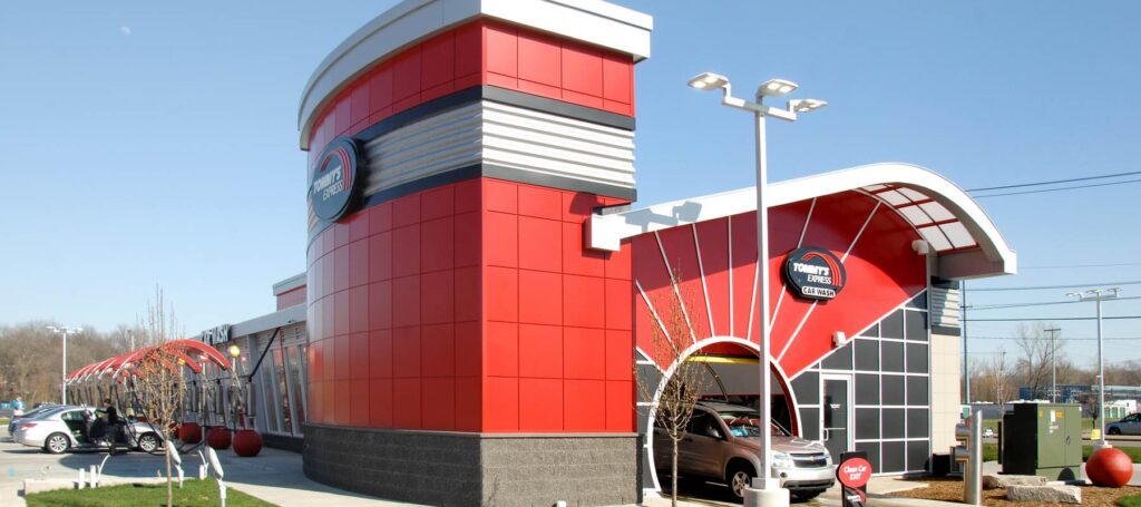 The Tommy&rsquo;s Express tower and sunburst arch entry with a vehicle heading into the wash tunnel